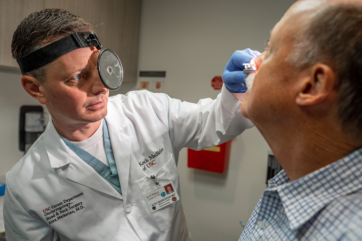 Dr. Alex Markarian, a Keck Medicine otolaryngologist, examines a male patient's nose for septoplasty treatment