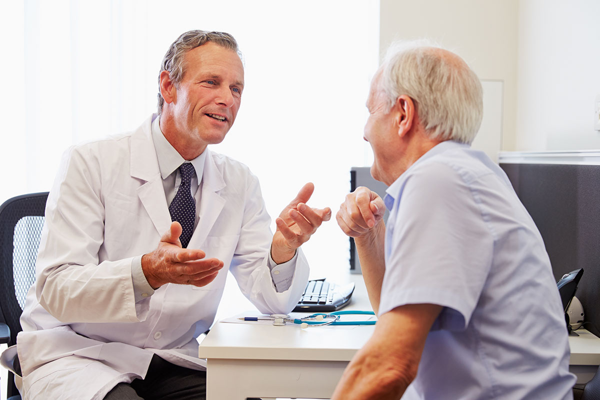 Doctor speaks to an older adult male patient in an office