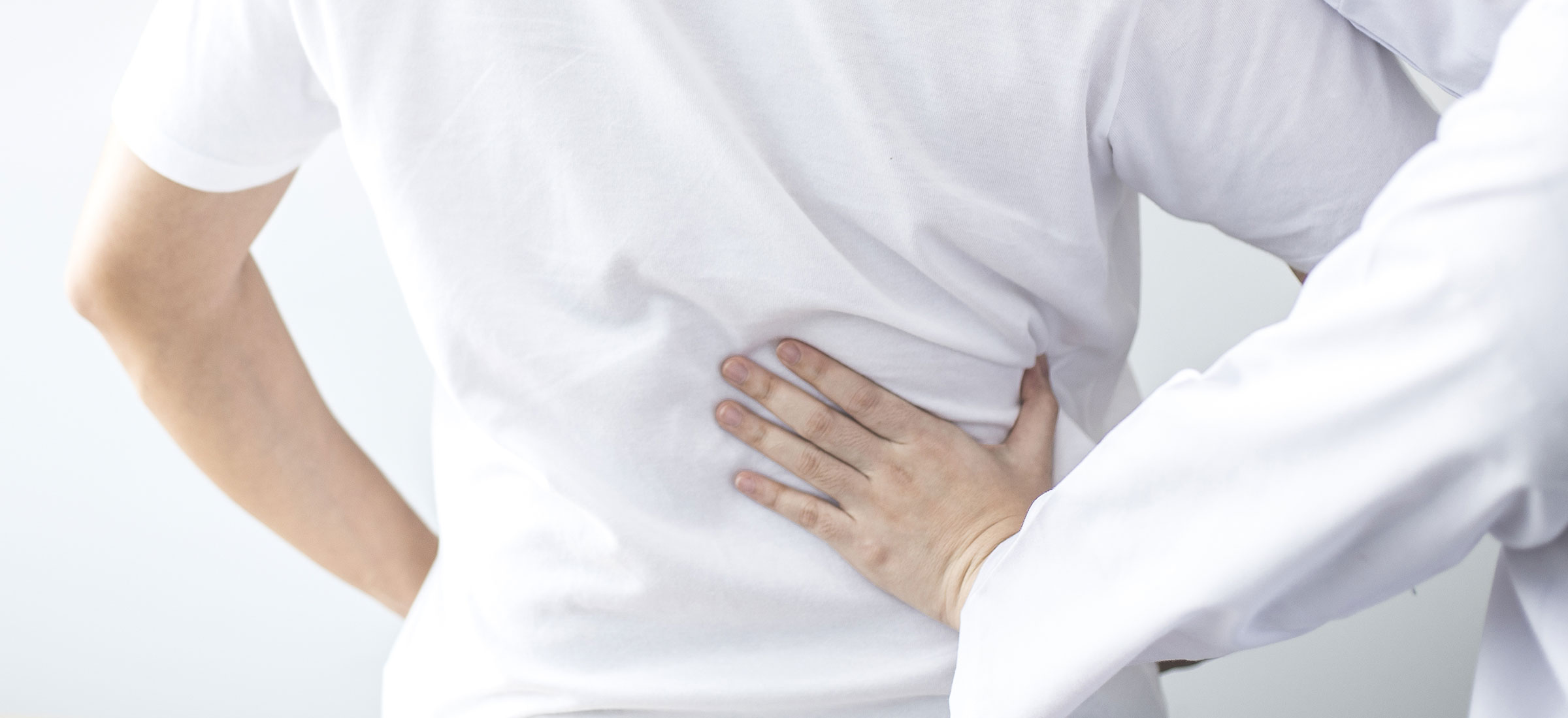 Physical therapist treats back pain for a male patient attending a rehabilitation center.