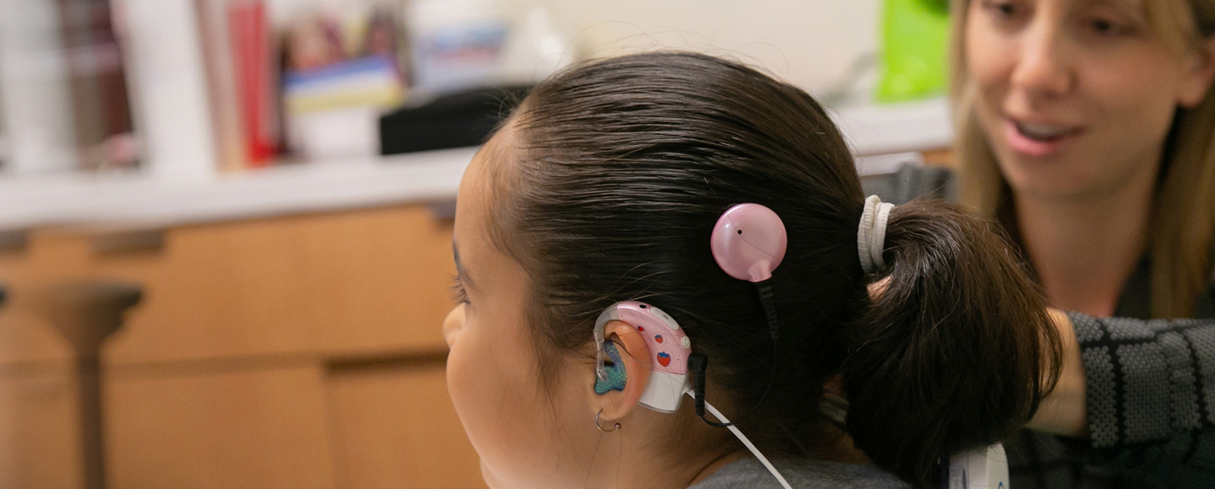 A minor wearing a hearing device is examined by a pediatric hearing loss specialist