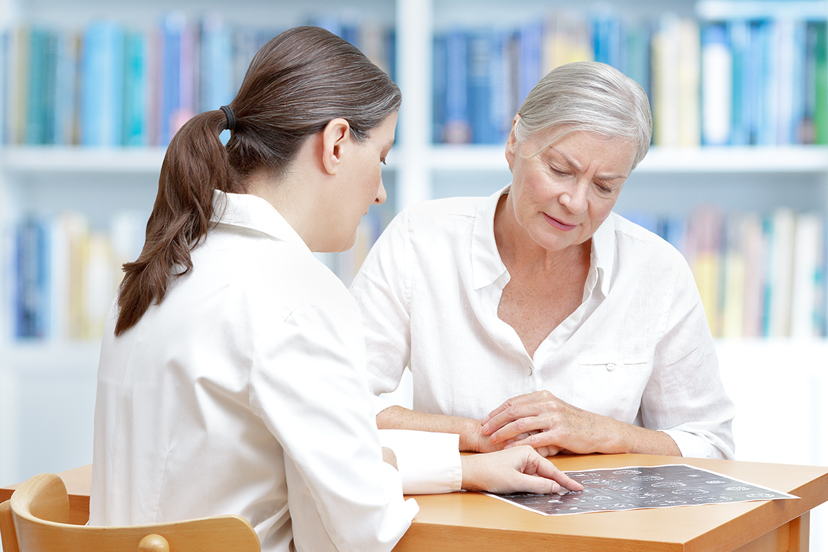 An older woman with a brain tumor discusses her brain scan with a female neurosurgeon