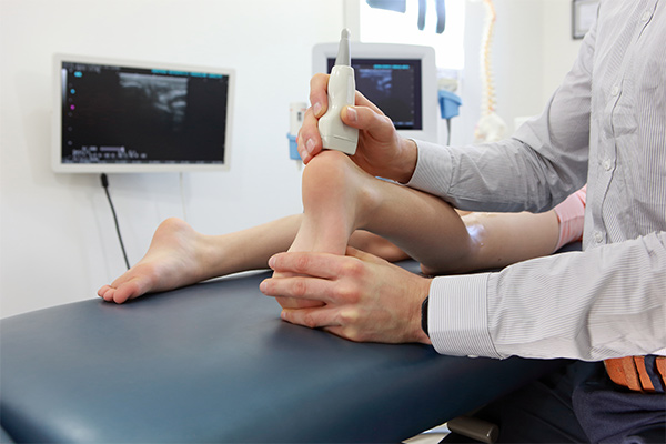 A doctor holds ultrasound equipment to a child's ankle.