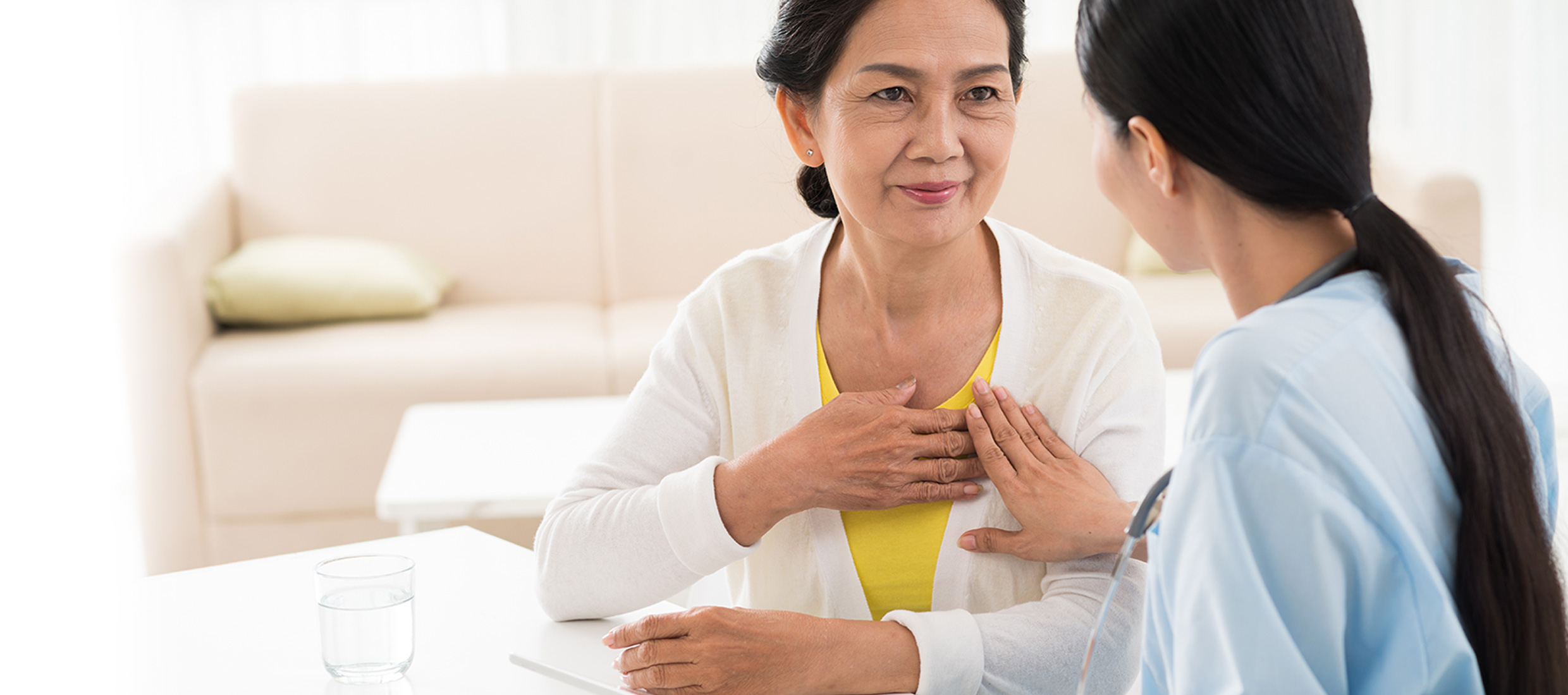 Female patient with arrhythmia touches her heart and female Keck Medicine AFib expert touches patient's hand