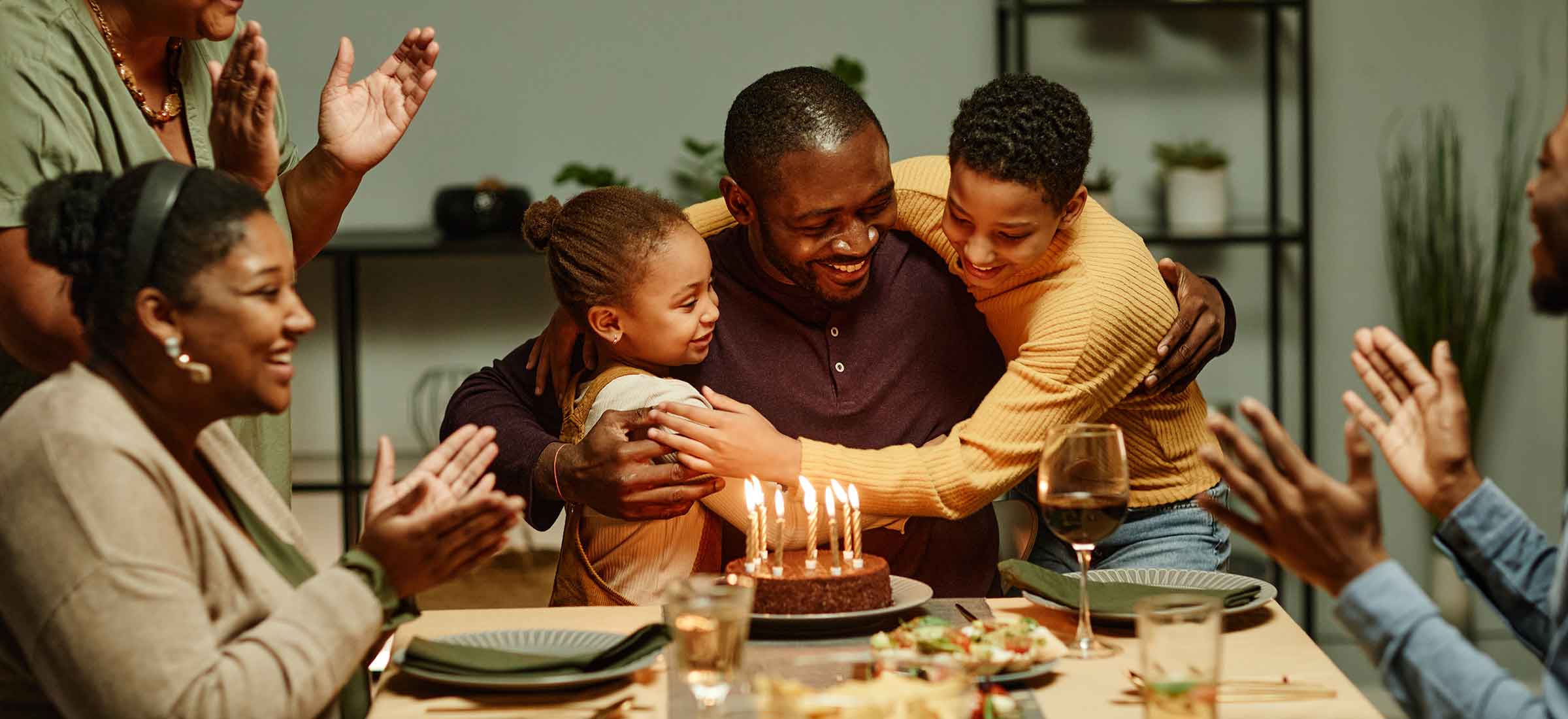 Portrait of smiling African American man embracing children while celebrating birthday with big happy family.