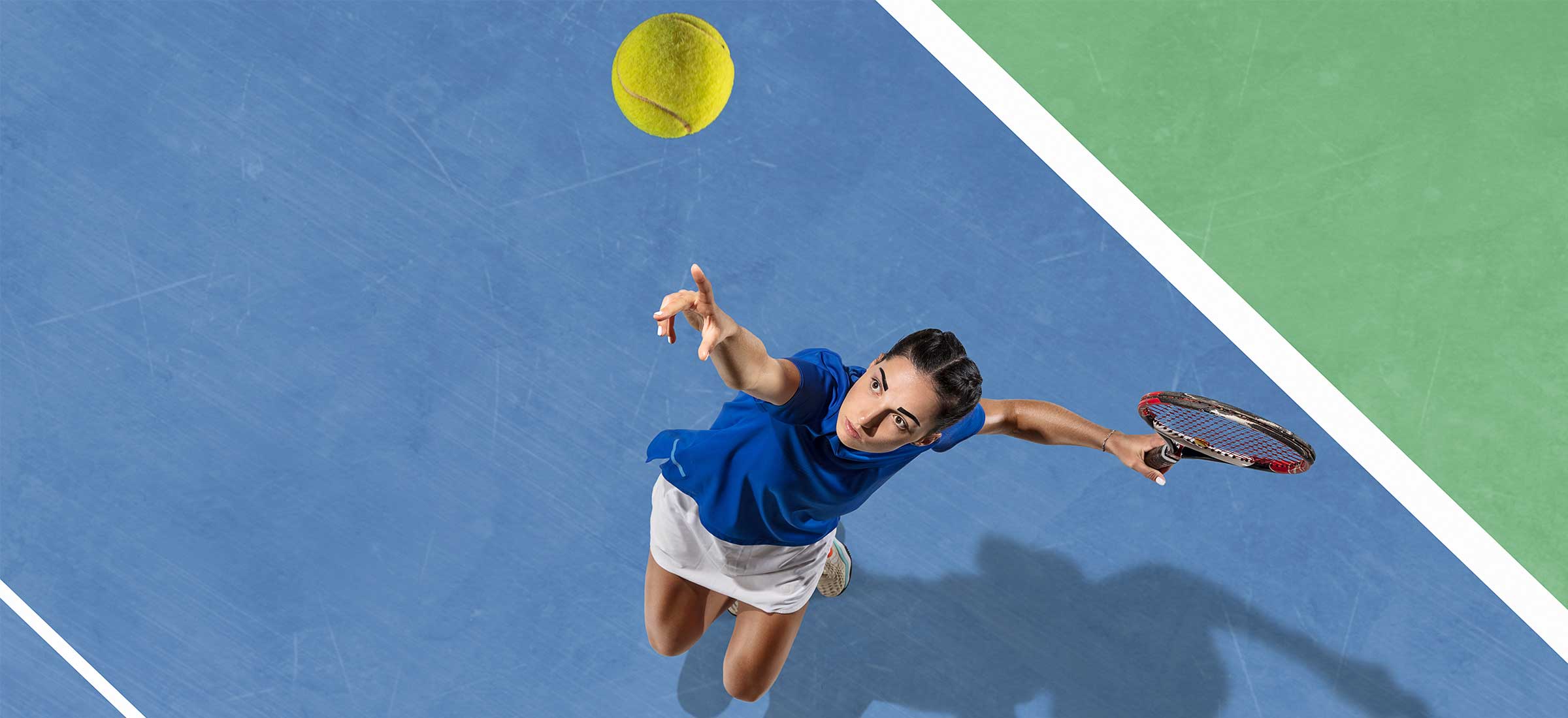 An overhead view of a woman hitting a tennis ball on a tennis court.