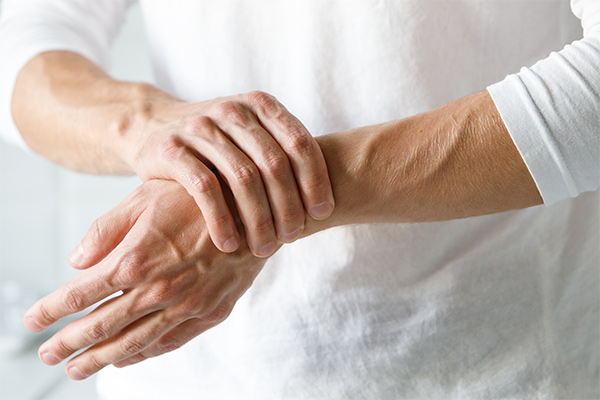 A picture of two hands with one hand grabbing the wrist of the other in pain.