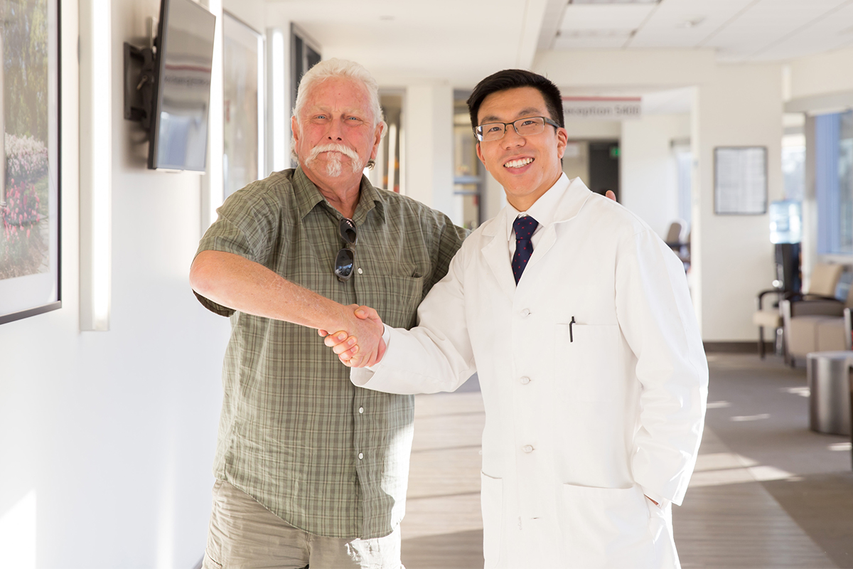 A senior male with a spinal cord injury shakes hands with a Keck Medicine of USC spine expert in a medical office