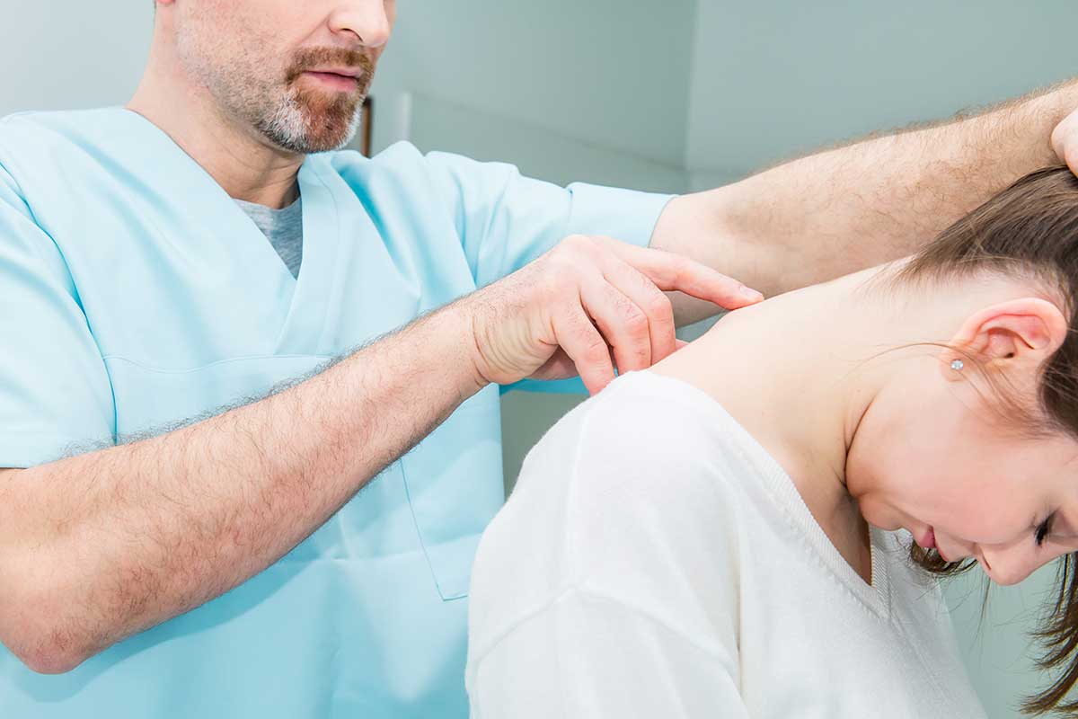 Close up of a male doctor examining the spinal column of a female patient in a medical clinic.