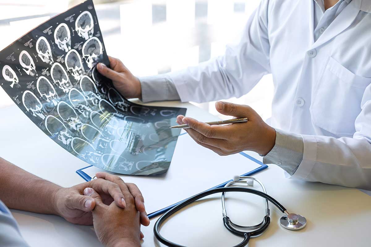 Doctor holding a brain scan and analyzing the results while discussing the exam with the patient.