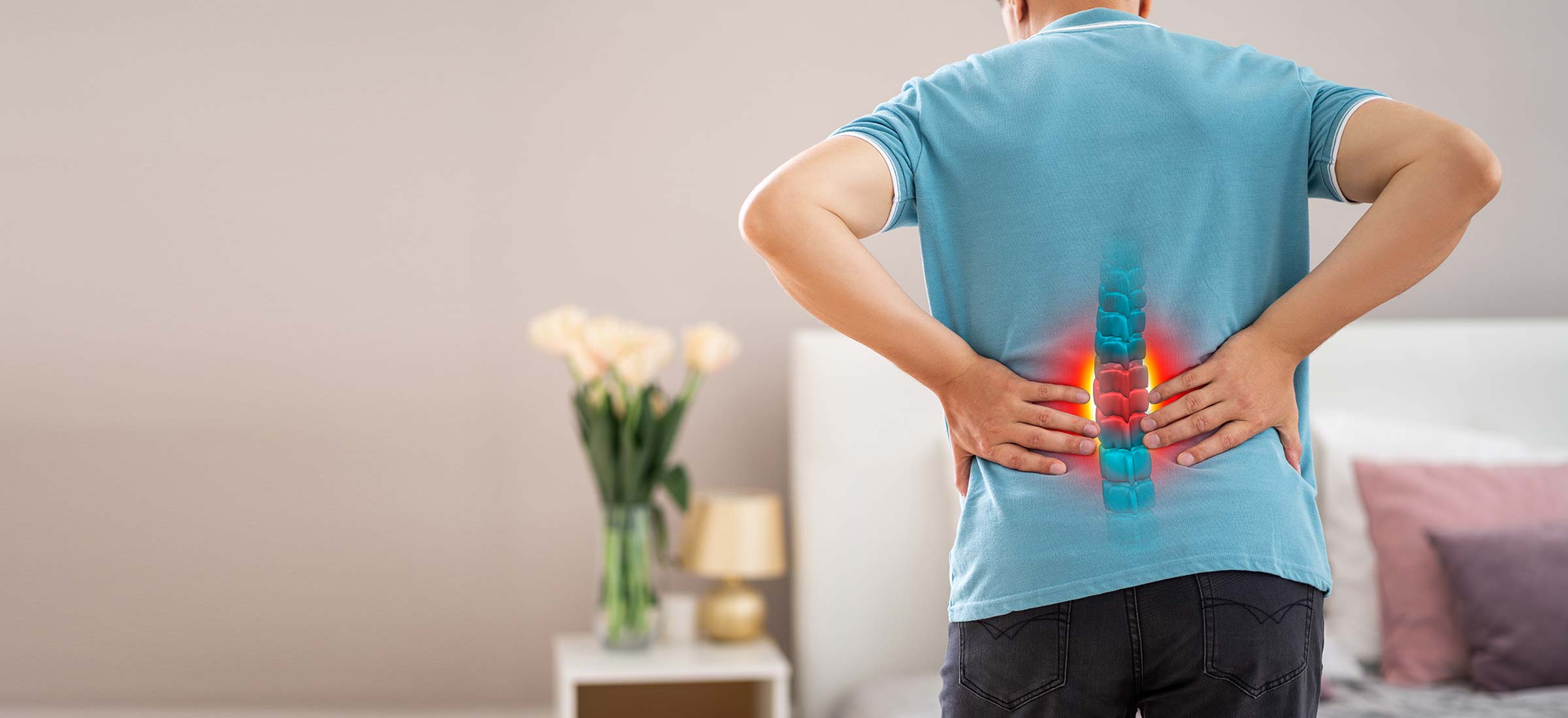A Keck Medicine degenerative disc disease patient with lower back pain holds his back near a drawing of his inflamed spine.