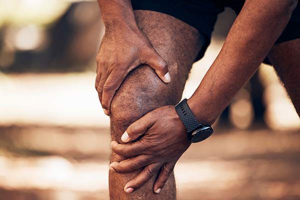 A man grabs his knee in pain.
