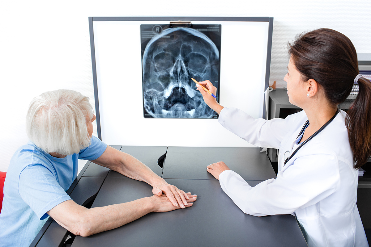 A female Keck Medicine Lothrop procedure specialist points to an X-ray of the sinuses with a senior sinus surgery patient