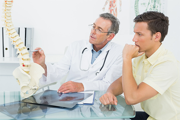 Doctor explaining spine to a patient in office.