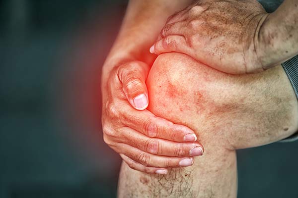 Hands hold on to a knee with a red graphic overlay.