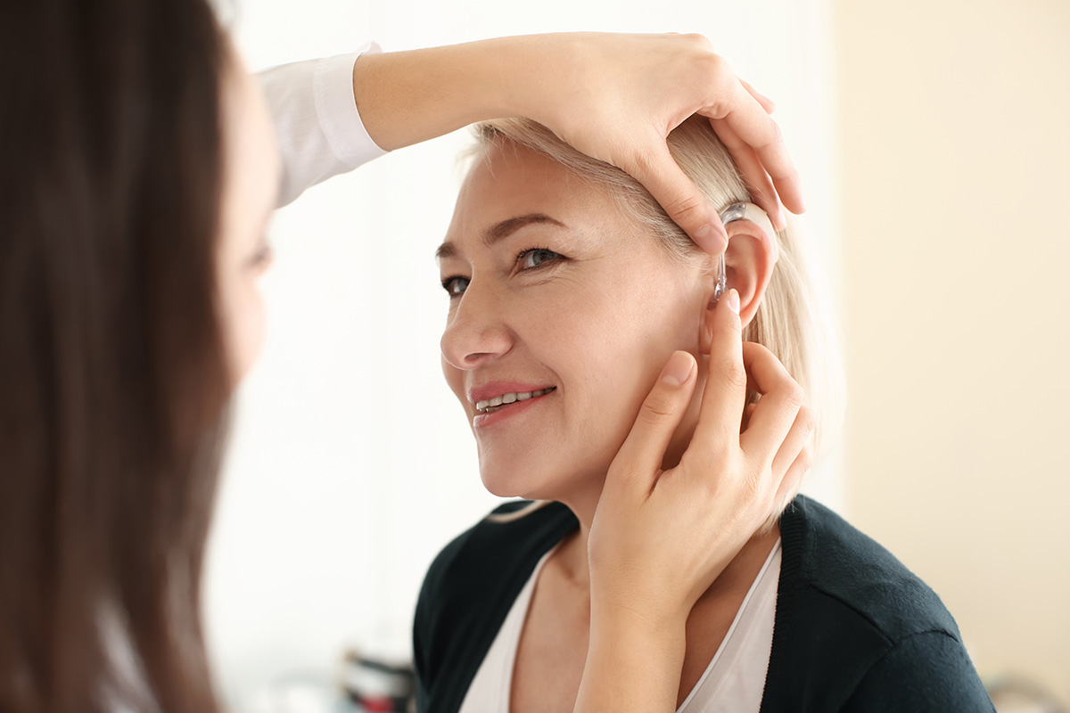 A female Keck Medicine of USC ossiculoplasty expert examines the left ear of a smiling female patient with hearing loss