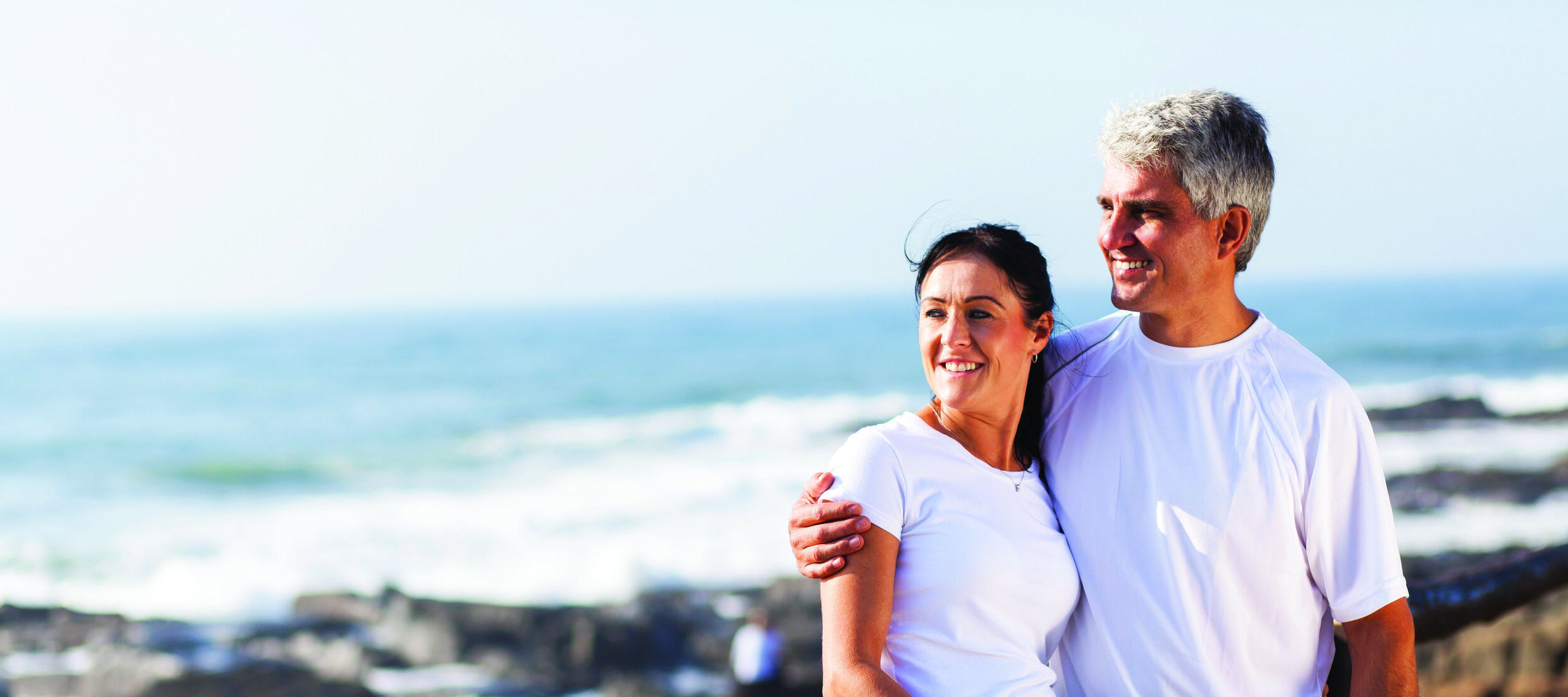 Man and woman hugging and smiling at the beach