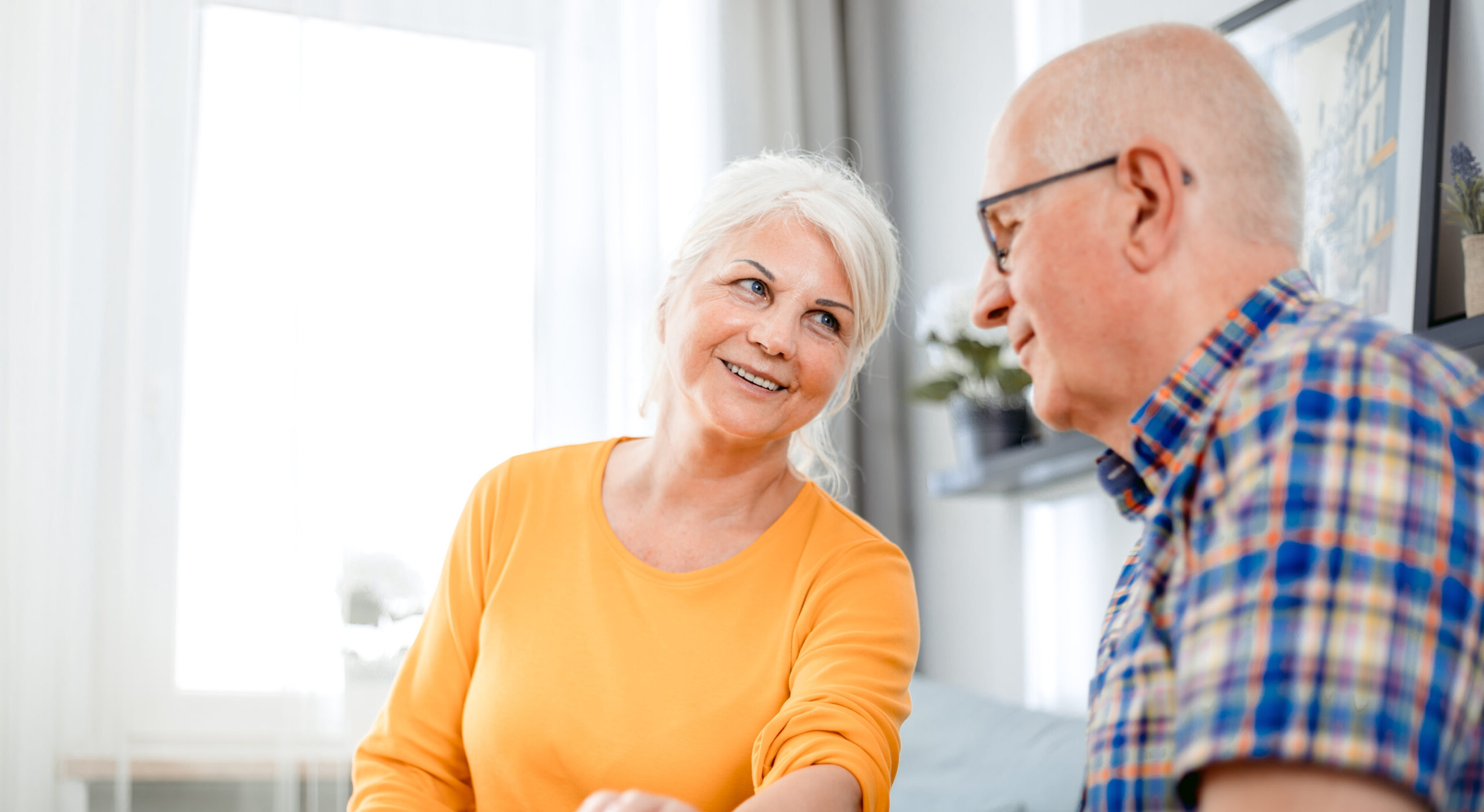 Two older adults talking to one another in a living room
