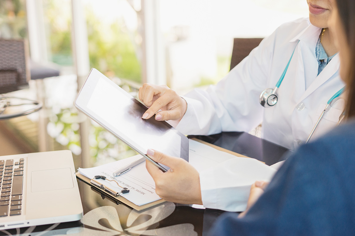 A female Keck Medicine GI cancer expert points to X-rays of a pancreatic cancer patient with a laptop in a medical office