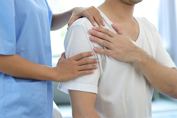 A doctor touches a patient's shoulder.