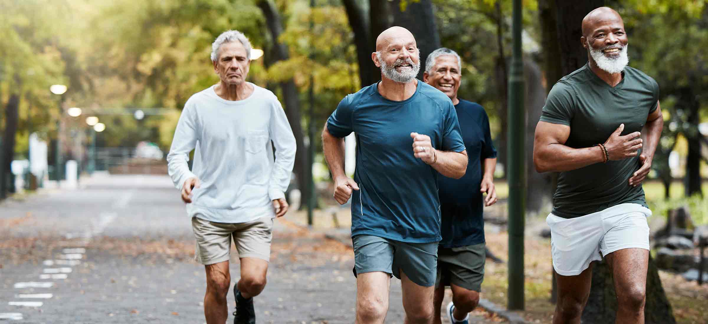 A group of senior men run through a park together.