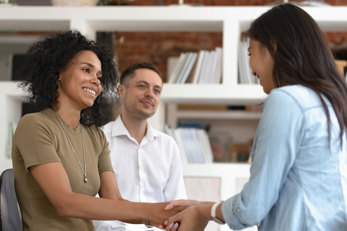 Two women and a man smile at one another while sitting in an office