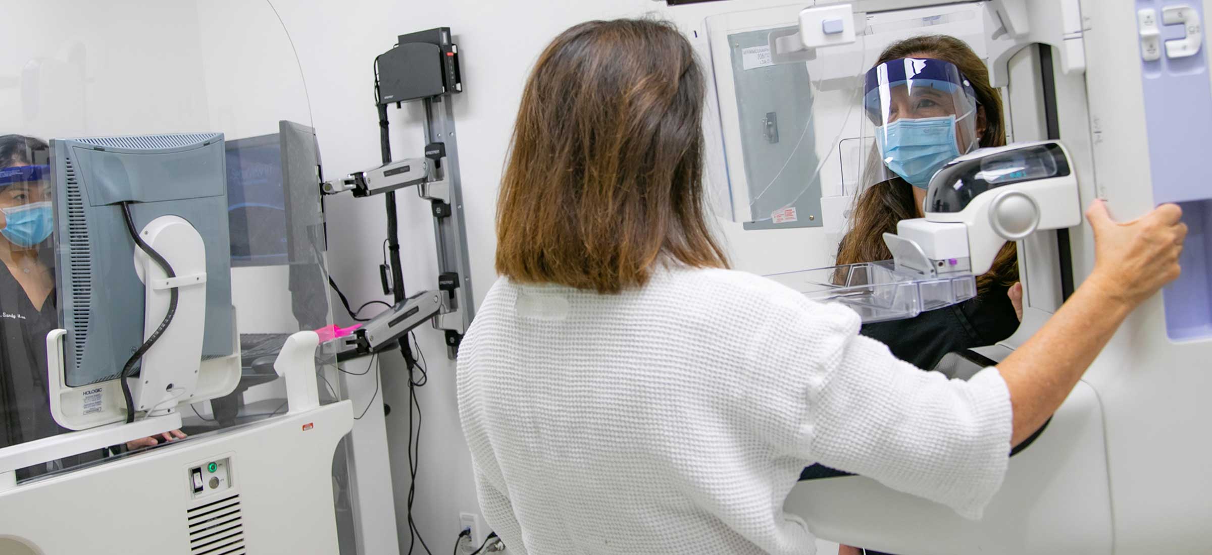 A female Keck Medicine doctor discusses radiology treatment with a patient in a mask and face shield near medical equipment.