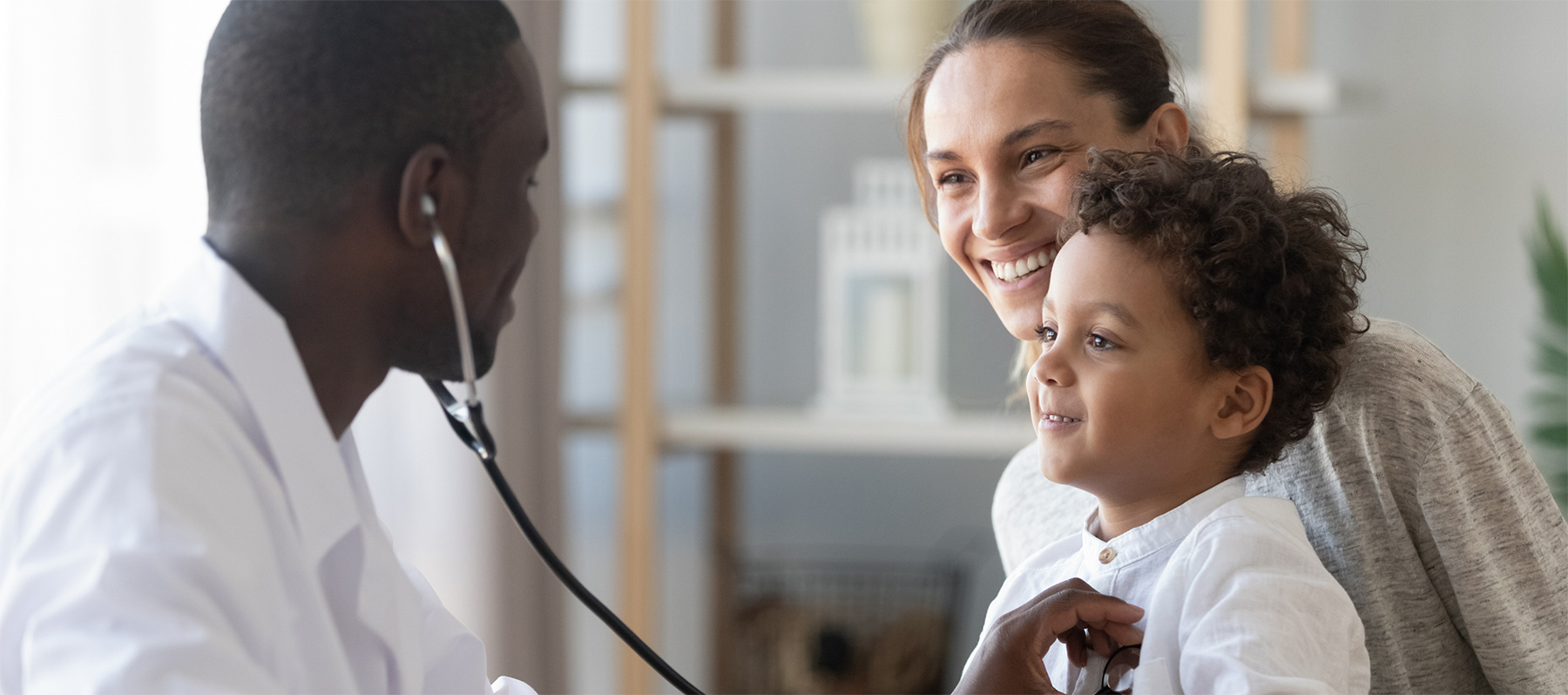 A mother holds her young son, while a Keck Medicine pulmonologist examines him for cystic fibrosis with a stethoscope