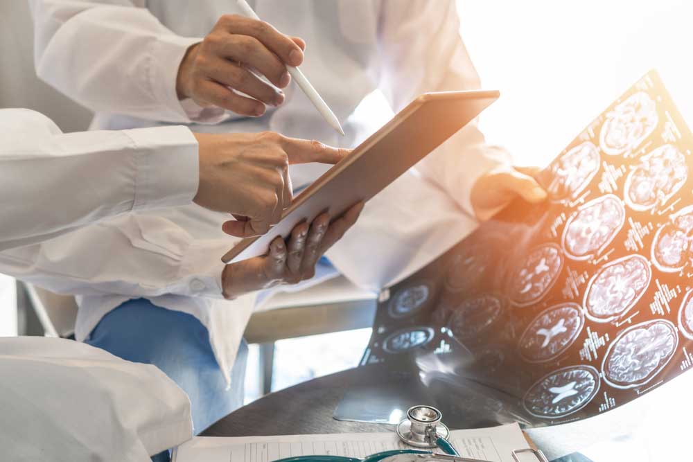 Doctors holding a digital tablet and scans of a patient's brain