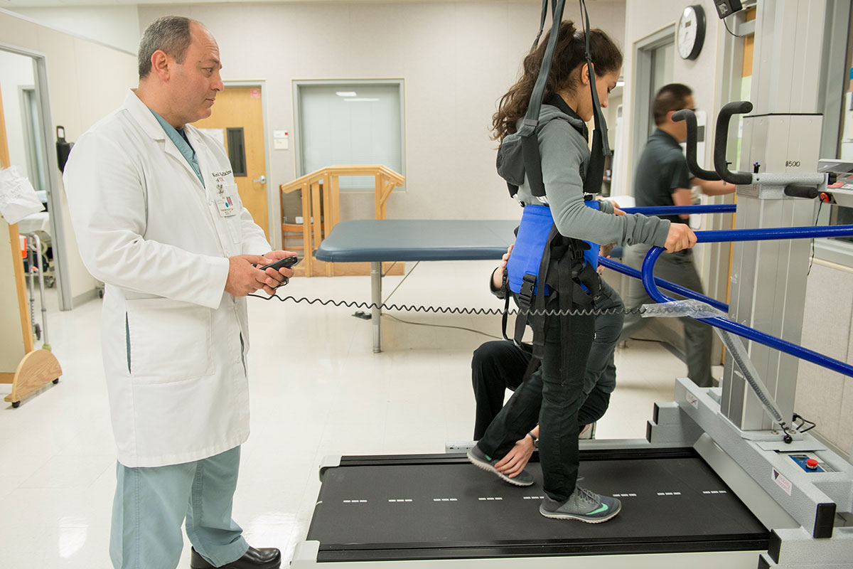 A man, doctor Ramzi Ben Youssef, helps a female patient receiving physical therapy at an inpatient rehab center