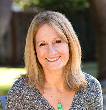Woman with blonde hair and sweater smiling