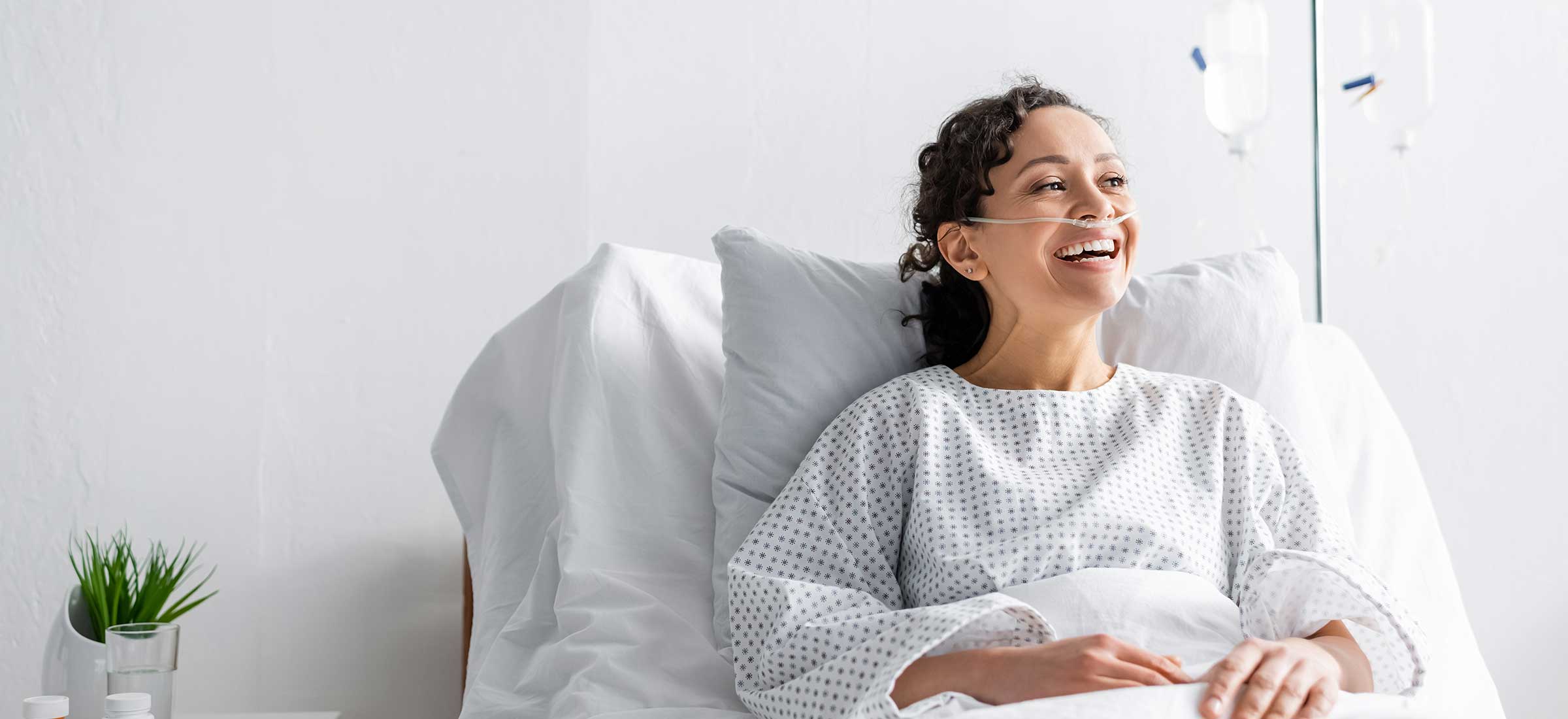 Happy African American woman laughing while sitting in hospital bed.