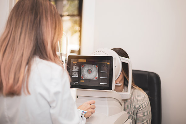 An optometrist uses a wide cone corneal topographer to take information from a patient's cornea.