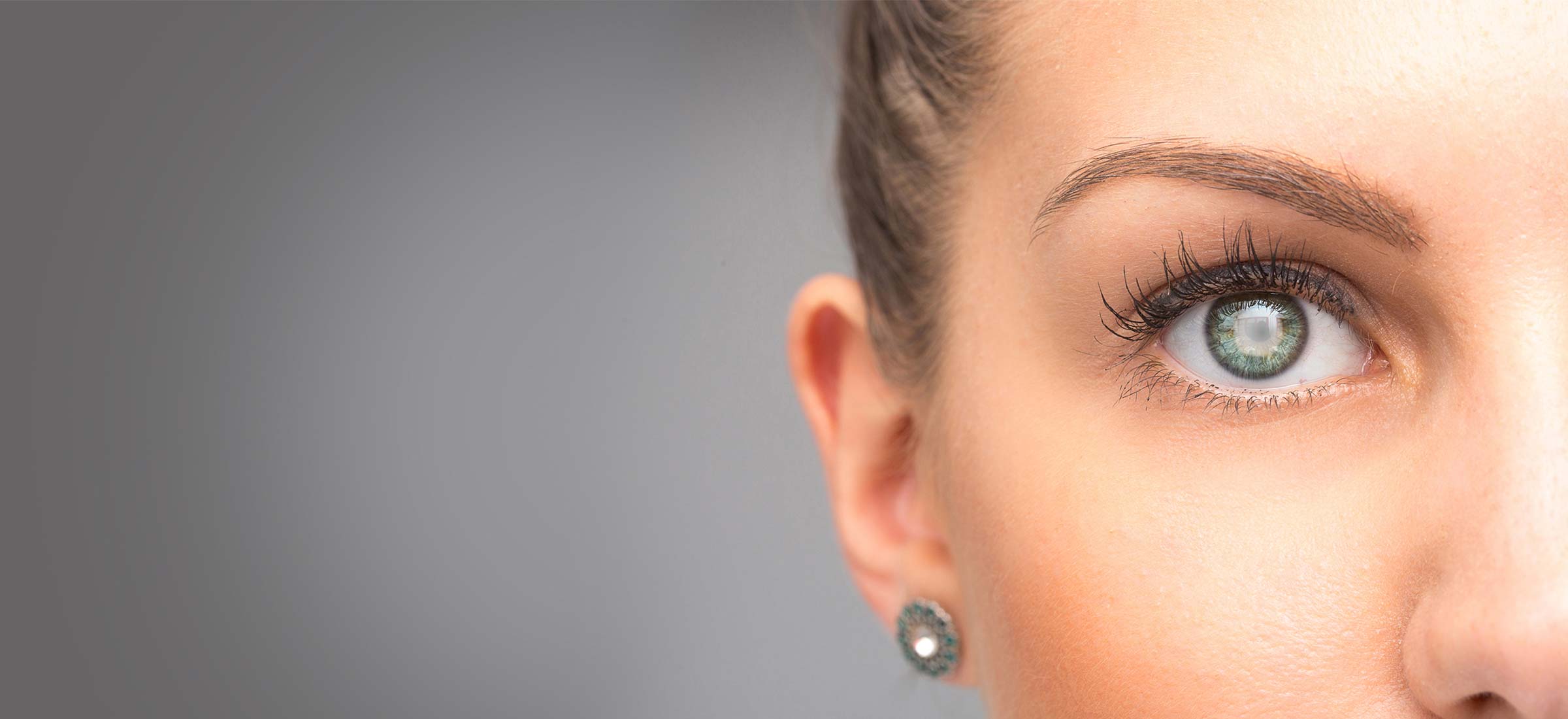 A light shines in a female glaucoma patient's right eye and is reflected in her diamond earring.