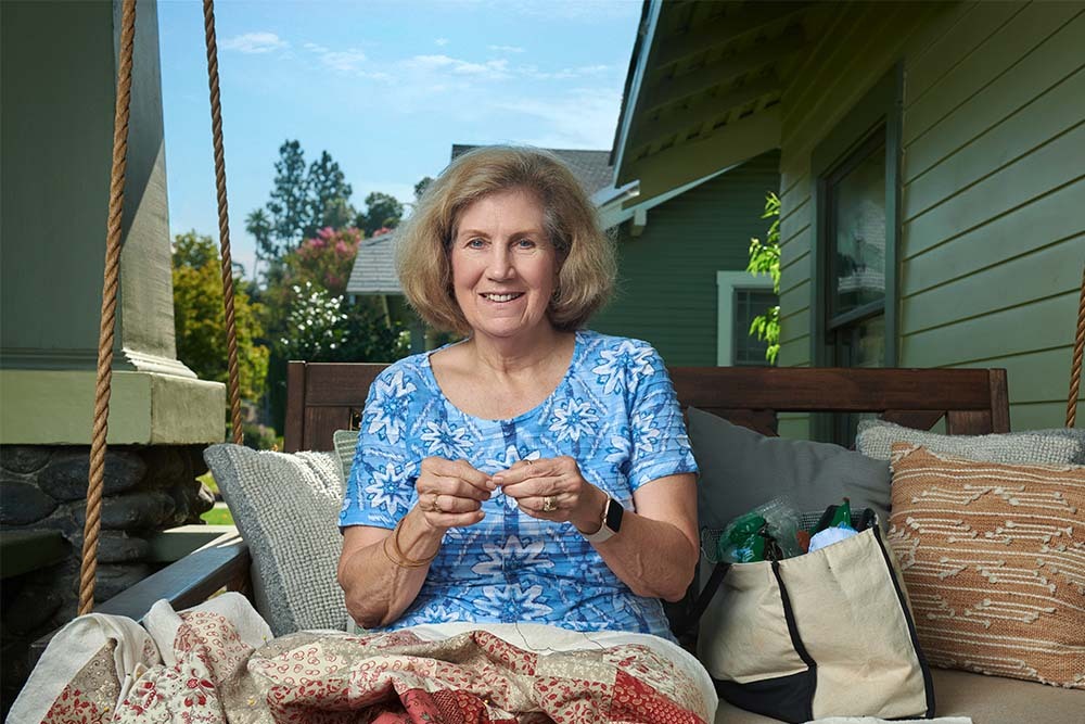 Victoria Farraj, an atrial fibrillation patient, sits on a porch swing knitting a quilt