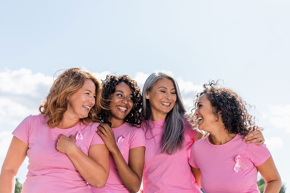 A diverge group of women wearing breast cancer awareness ribbons standing together outside