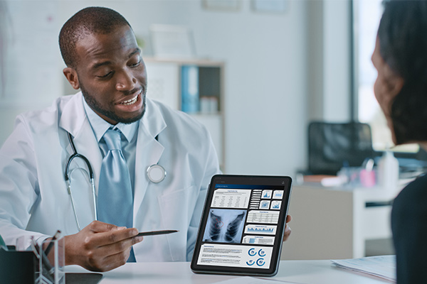 Female patient listens to pulmonologist, who is using a digital tablet to show lung analysis results.