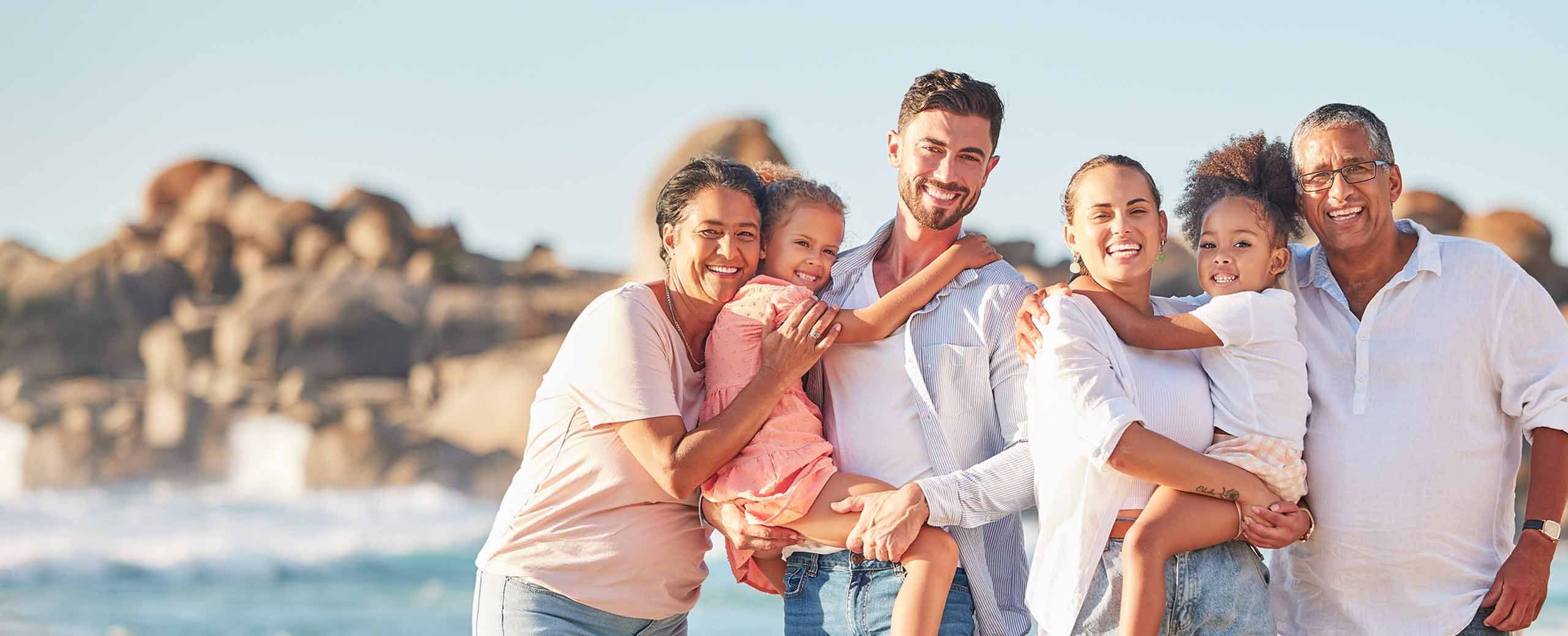 Happy family, including adults and children, stand together by the sea