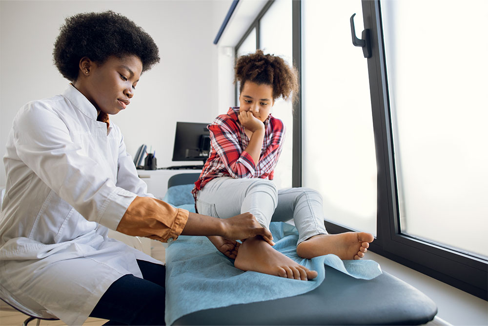 A doctor touches a young woman's ankle.