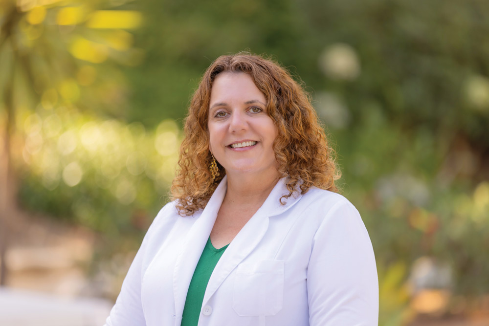 Oncology nurse navigator Alison Ambrose smiles in an outdoor portrait, wearing a white Keck Medicine labcoat