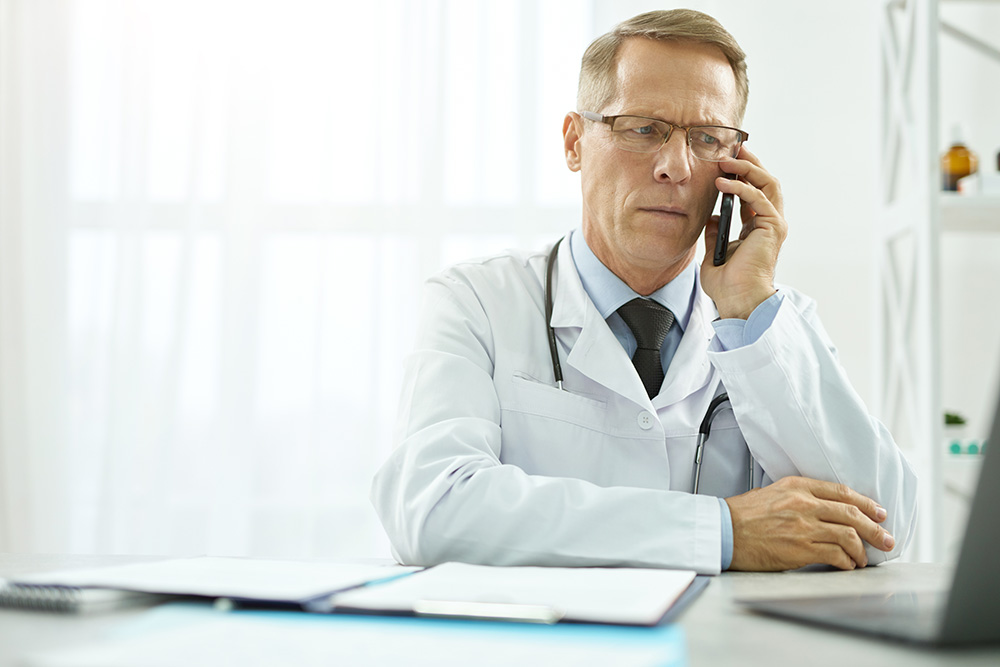 Doctor on phone having trouble trying to transfer a lung transplant patient to a transplant center.