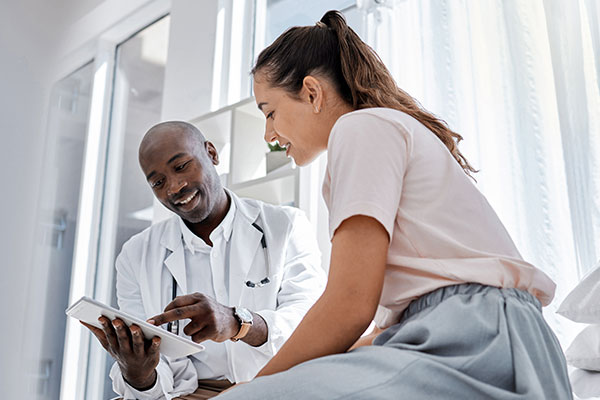 Male doctor counsels young adult female patient in office.