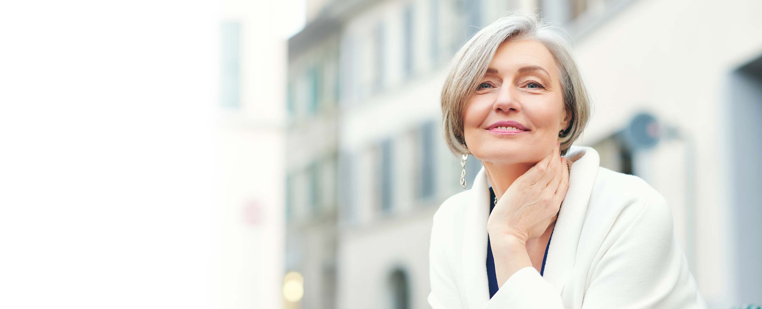 A woman smiles in front of a building.