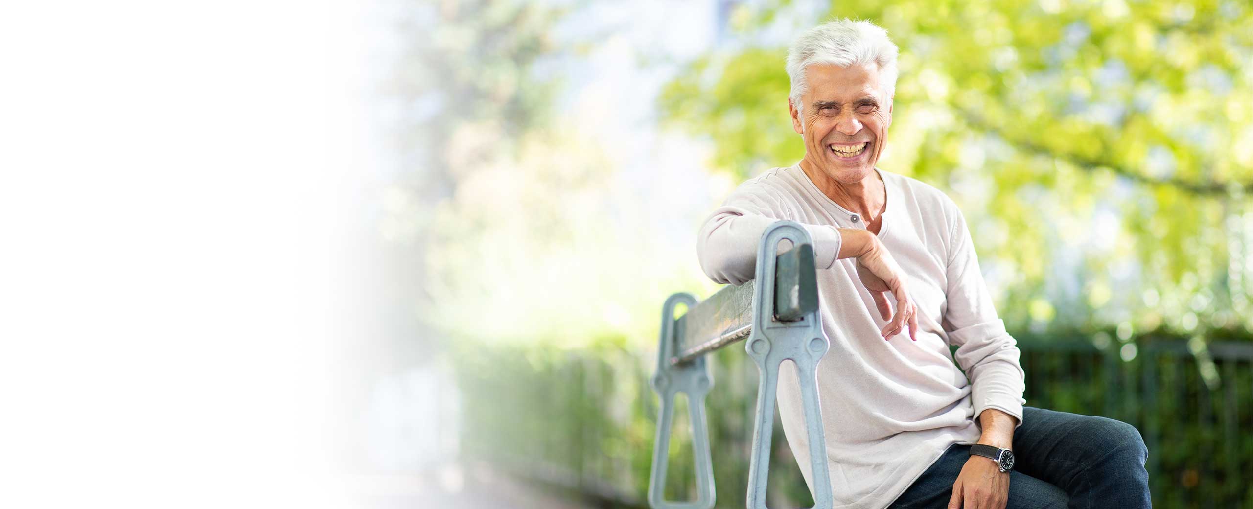 A man sits on a bench and smiles.