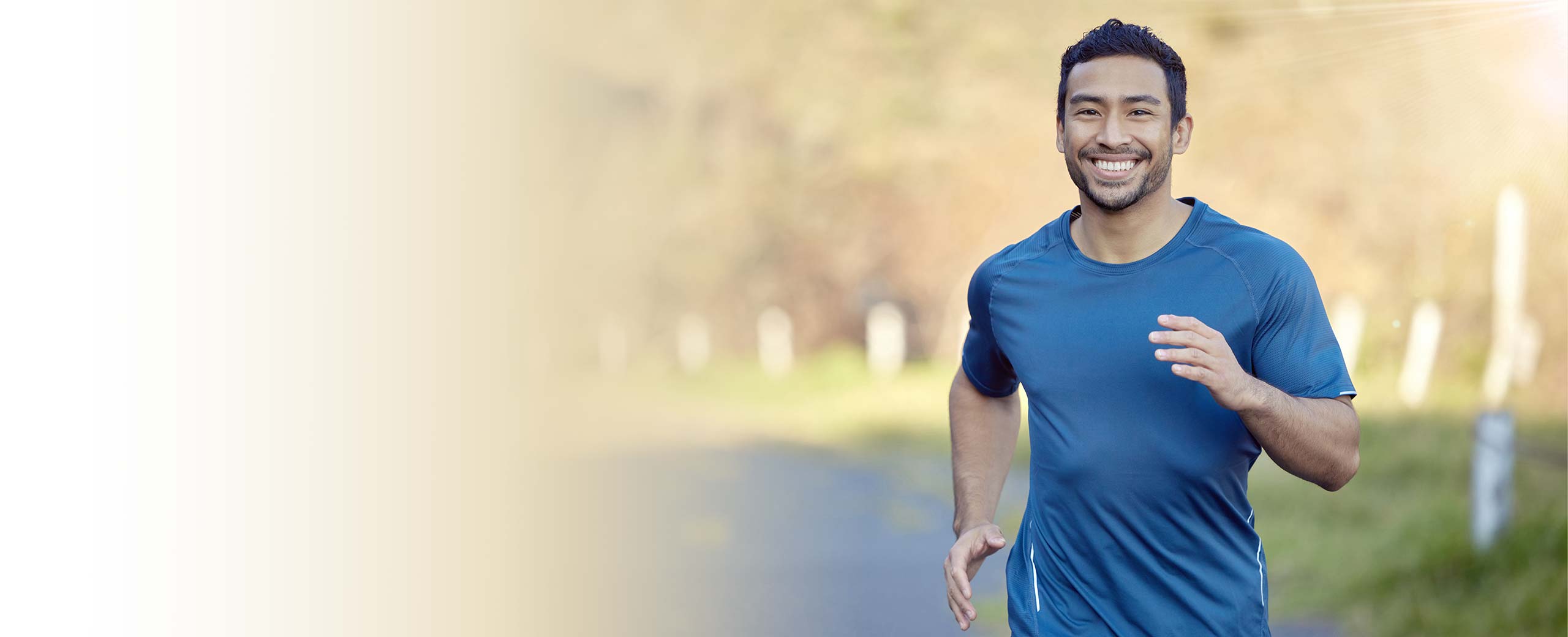 A man runs through a park and smiles.