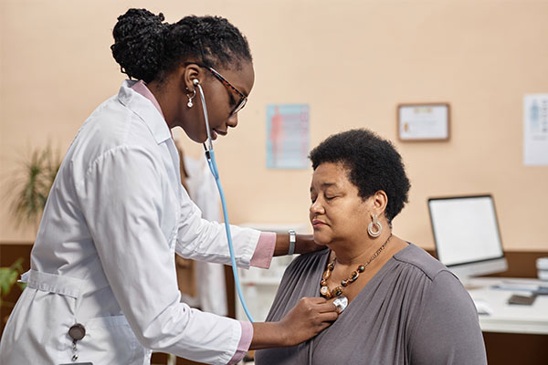 A doctor checks a woman's heart during a consultation for a coronary artery bypass grafting (CABG) procedure.