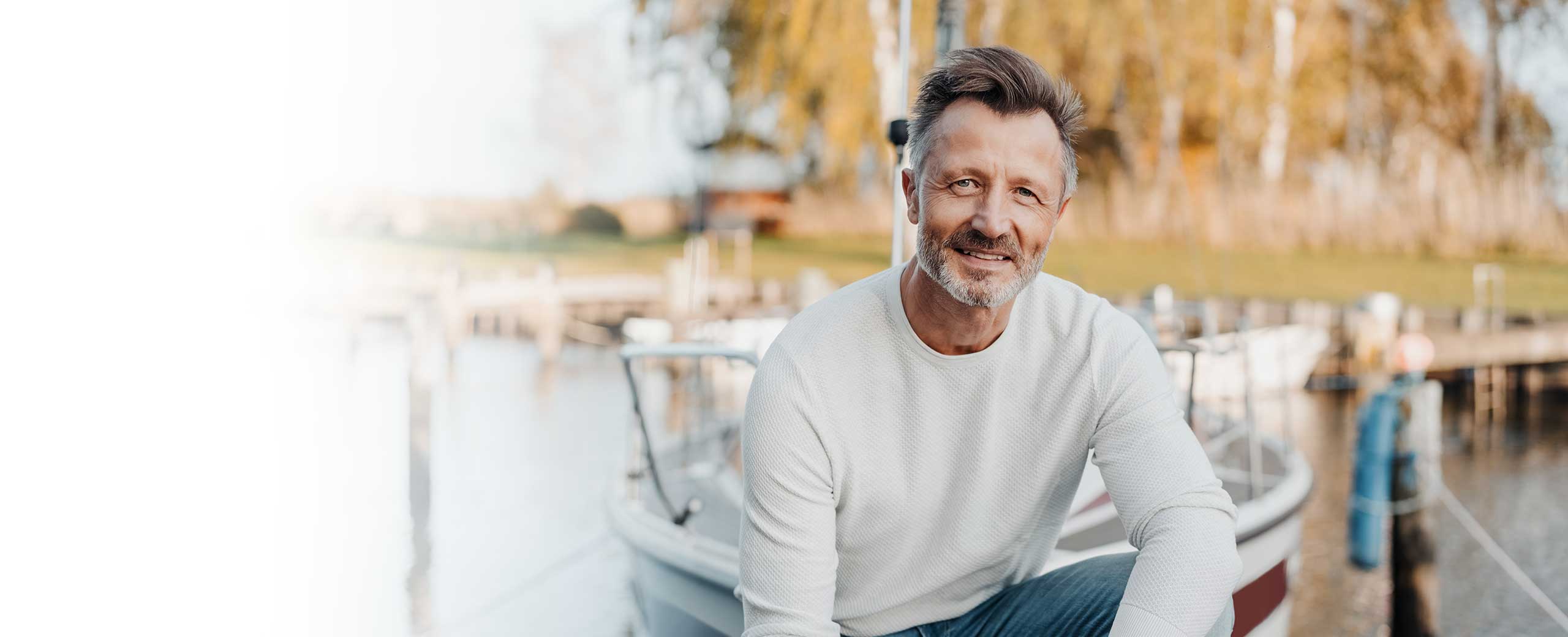 A man smiles while sitting outside.