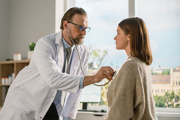 A doctor checks a woman for genetic cardiovascular conditions.