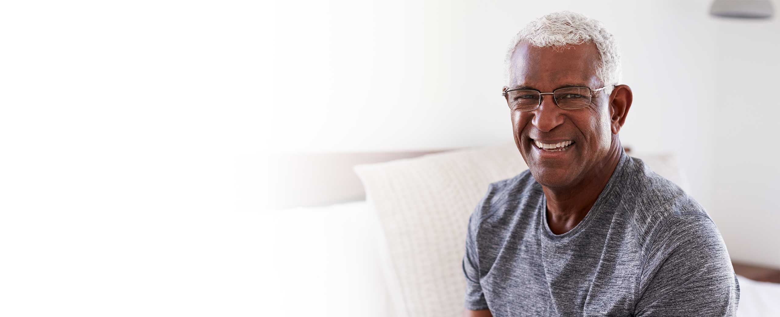 A man smiles while sitting on a couch.