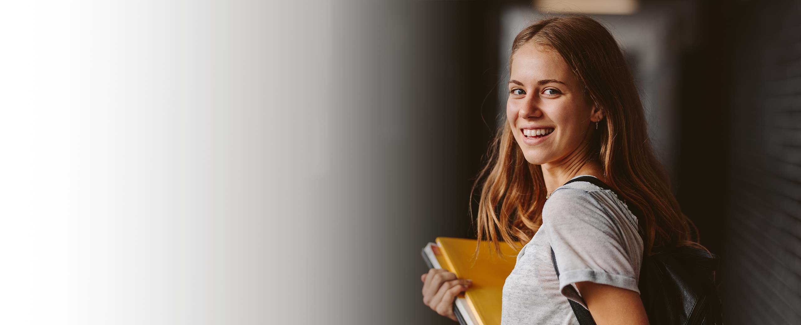 A woman holds some notebooks and smiles.